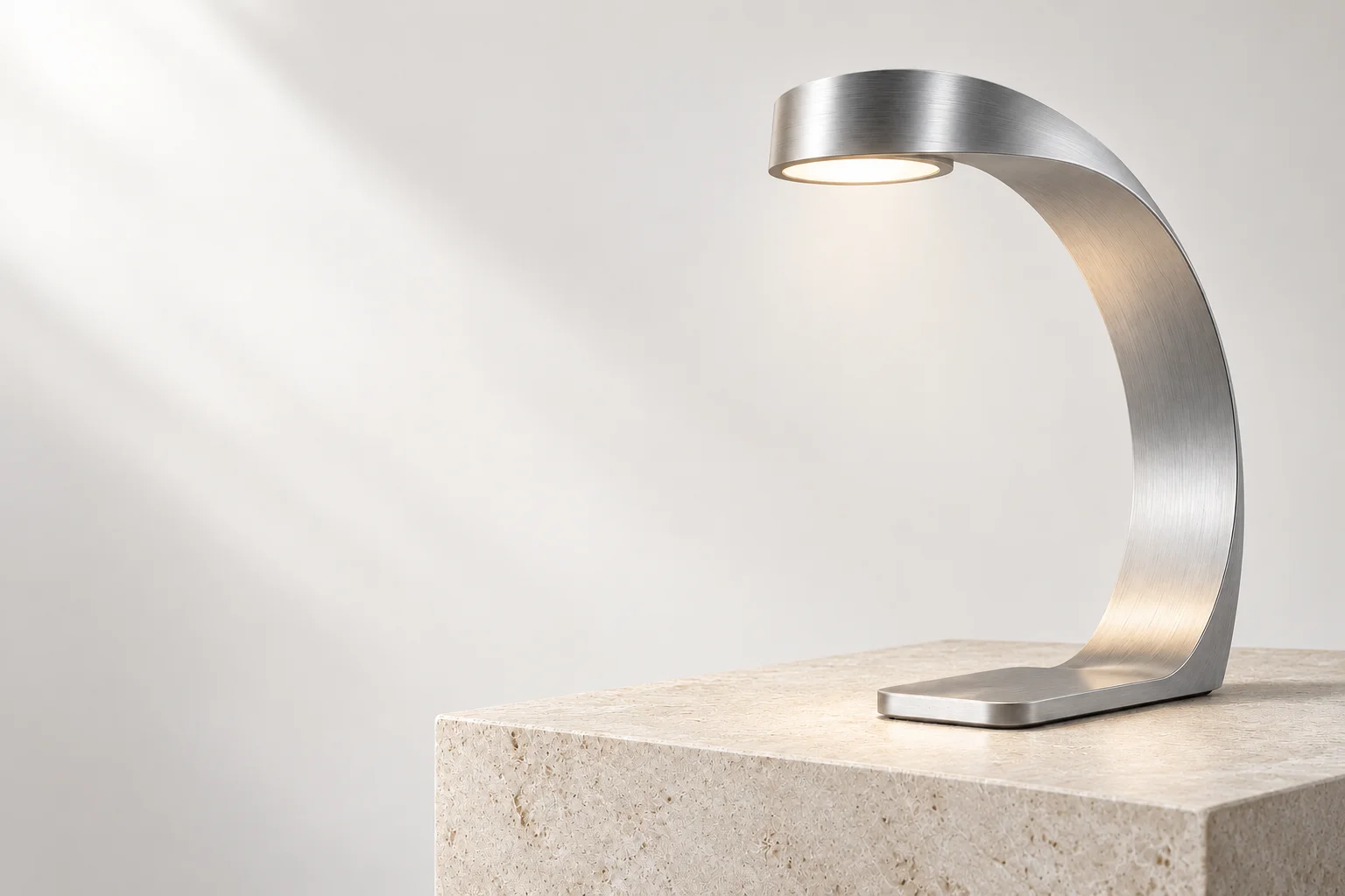 Sculptural brushed aluminum lamp on a stone plinth